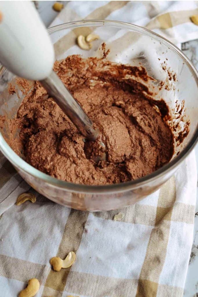 using an immersion blender to blend the date chocolate cake filling