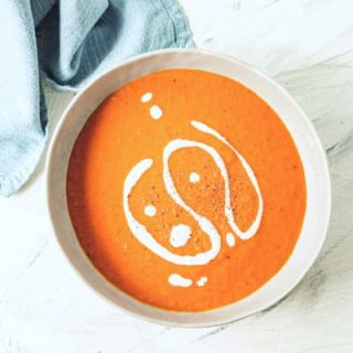 vegan tomato soup in bowl with coconut cream drizzle on top