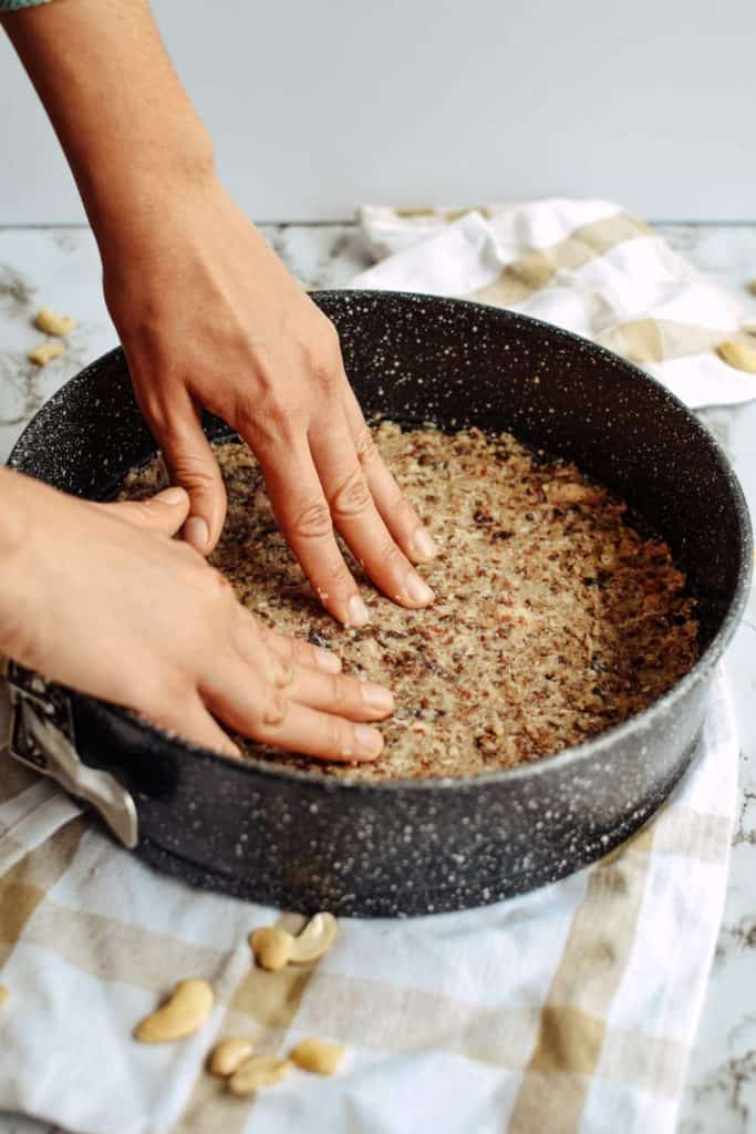 pressing the raw nut crust into a cake pan