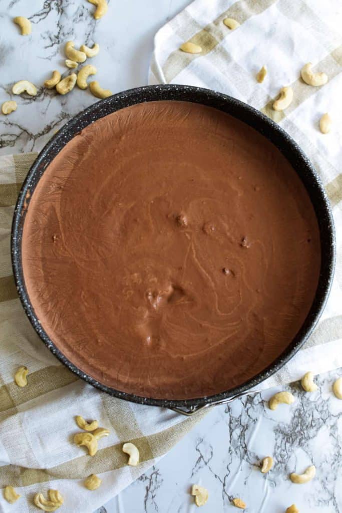 raw chocolate cake in cake pan after being chilled in fridge for a few hours