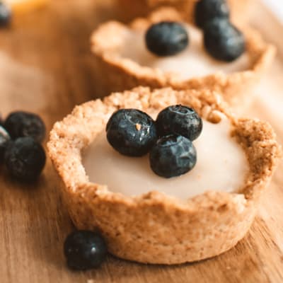 closeup of lemon coconut tartlets with nut crust and blueberry topping