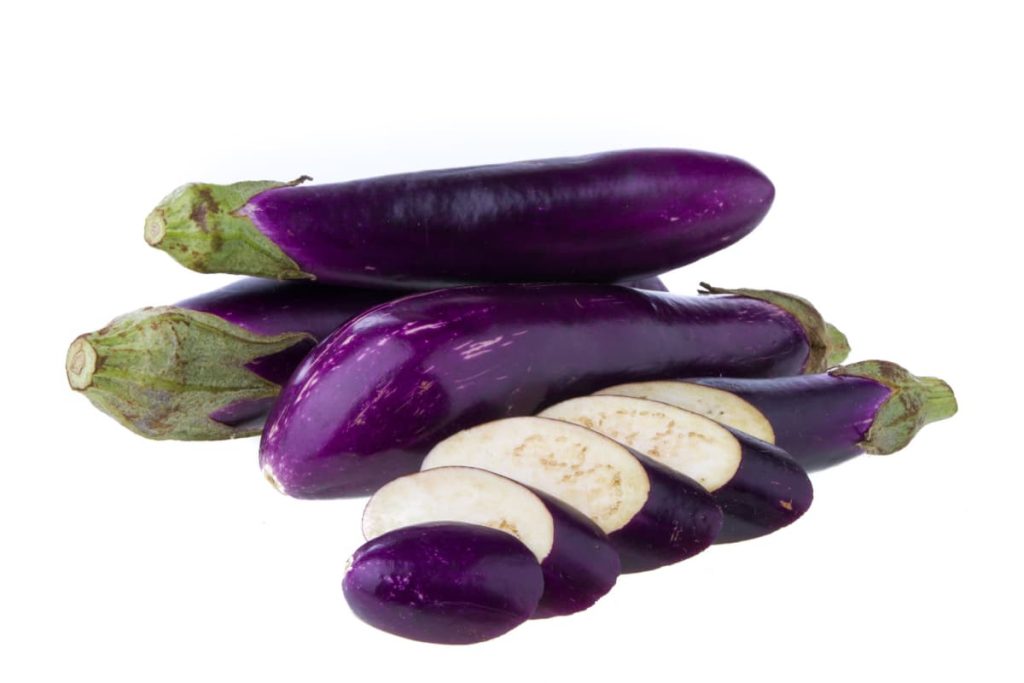 eggplant in a pile whole and sliced on white background
